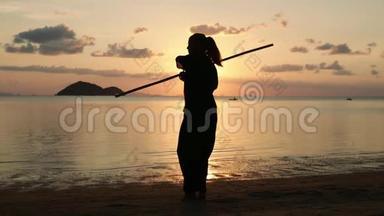 一位年轻有权势的女人在海滩上做<strong>功夫</strong>练习的<strong>剪影</strong>